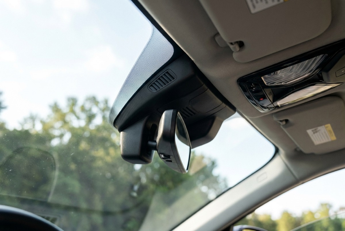 Illustration of the camera and sensor housing behind a car's rear-view mirror at the top of the windshield
